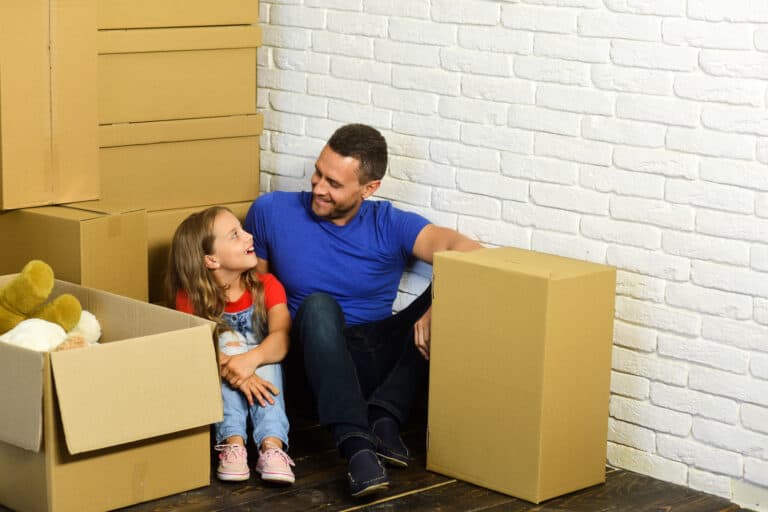 A father and a daughter surrounded by cardboard boxes in the concept of a moving day