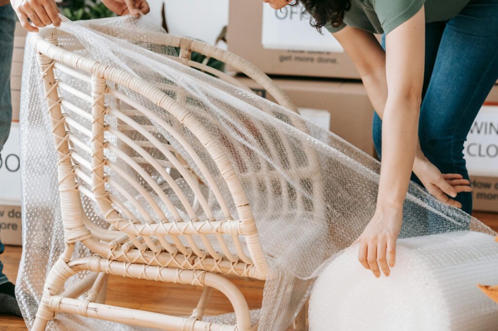 Two movers wrapping a chair with bubble wrap in the concept of man and van in Twickenham.
