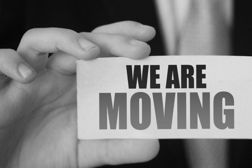 A businessman holding a card with texts, 'We are moving', in the concept of 'how to plan and coordinate an office move'.